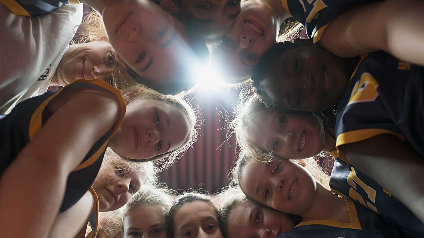 女篮球运动员和教练围成一圈。图片来源:Joos Mind, Getty Images