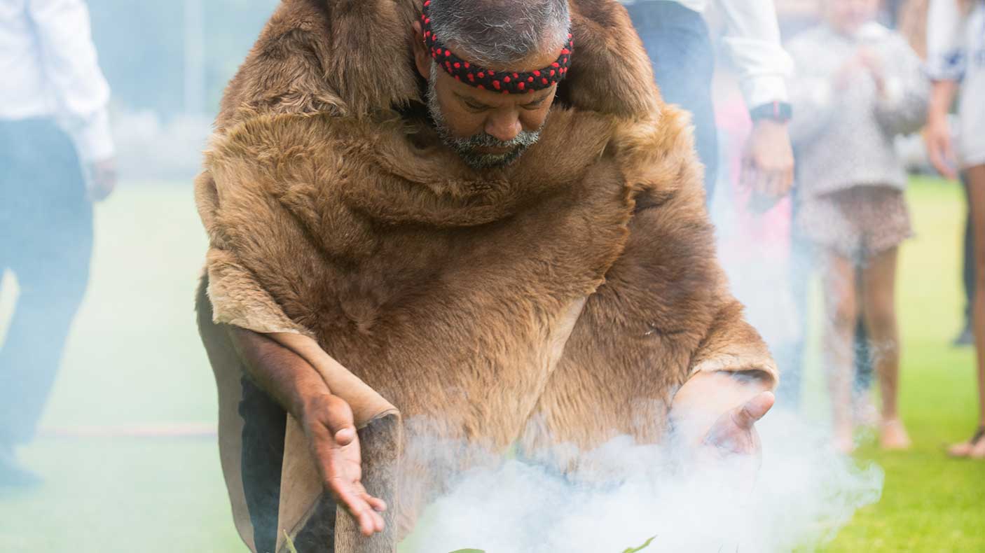 一位穿着传统服饰的土著男子正在进行吸烟仪式