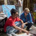 2019年艺术市场揭秘。摄影:Steph Pease两个人在看一幅放在地上的油画。