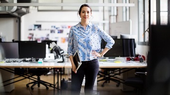 肖像自信的女企业家站在臀部，手拿着数字平板电脑在创意办公室