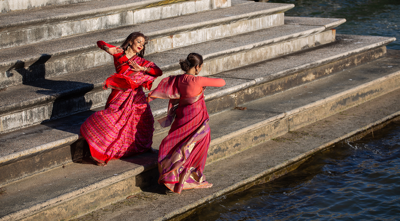 两名身穿传统服装的印度女舞者在河边跳舞。